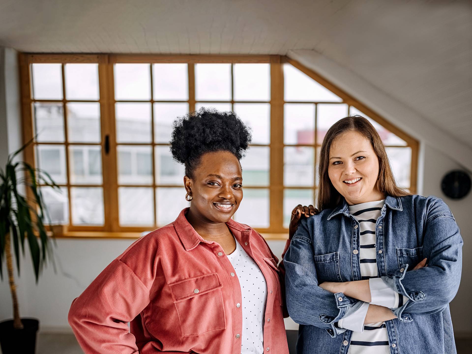 Portrait of two female coworkers standing together with smiles